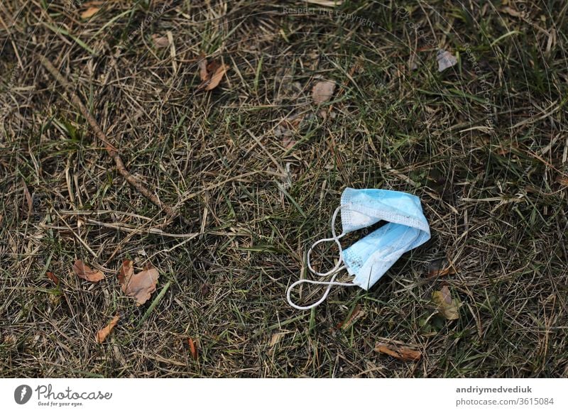 Dirty used medical mask lying on the ground, grass on background. Coronavirus panic. copy space. selective focus health illness prevention coronavirus disease