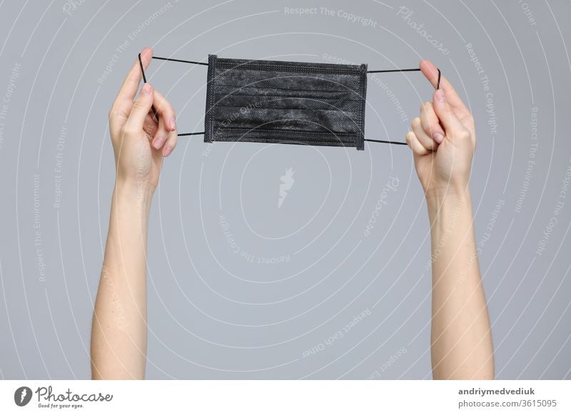 Woman hands holding a facial medical mask on grey background, close up, copy space, Flu epidemic, allergy season, protection against virus - Covid-19 and coronavirus