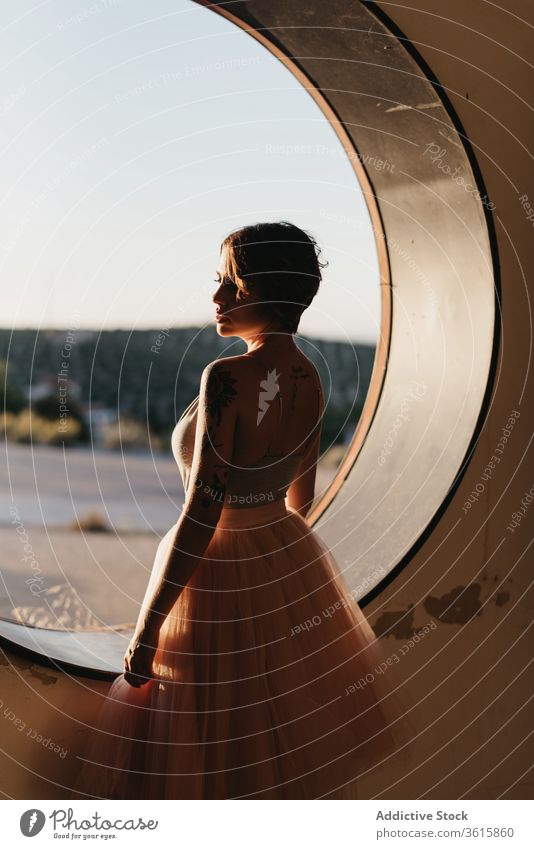 Relaxed female dancer looking at round hole woman grace relax dream pensive serene art creative window nature elegant slim sensual tranquil rest calm fantasy