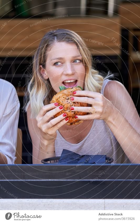 Amazed woman eating meal in cafe excited together window lifestyle share burger enjoy meeting grimace lunch expressive restaurant modern contemporary female