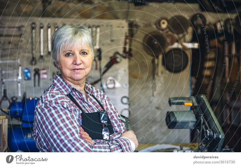 Female carpenter in his workshop woman mature waist up portrait carpentry looking camera holding caliper posing work bench wood worker smiling craft occupation