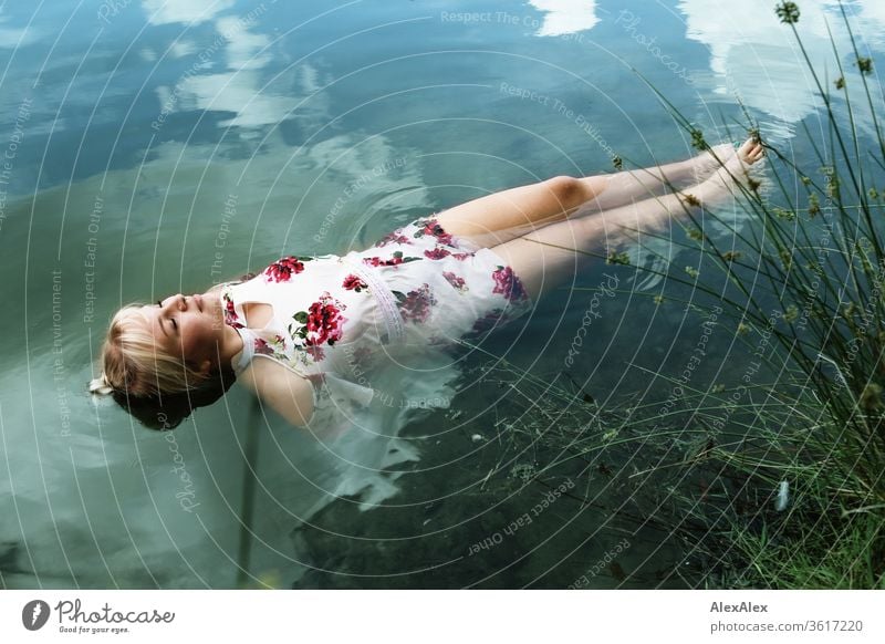 Portrait of a young blonde woman in a white summer dress in a lake on the surface girl Young woman already Blonde long hairs youthful 19 18-20 years