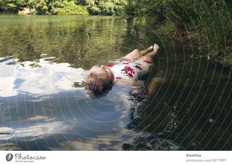 Portrait of a young blonde woman in a white summer dress in a lake on the surface girl Young woman already Blonde long hairs youthful 19 18-20 years