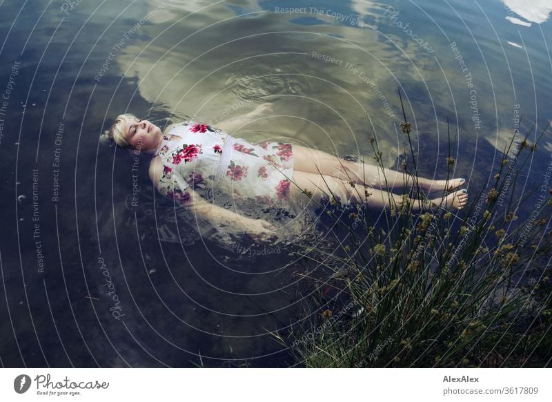 Portrait of a young blonde woman in a white summer dress in a lake on the surface girl Young woman already Blonde long hairs youthful 19 18-20 years