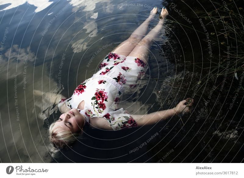 Portrait of a young blonde woman in a white summer dress in a lake on the surface girl Young woman already Blonde long hairs youthful 19 18-20 years