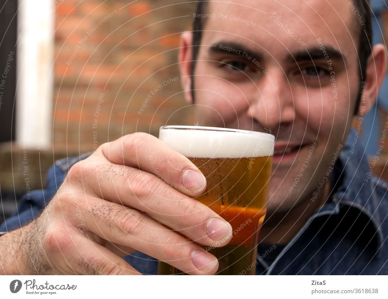 Man with beer man alcohol drink drinking pub raise glass raising hand holding male alcoholic happy relaxing chilling cold beverage addiction social party cheers