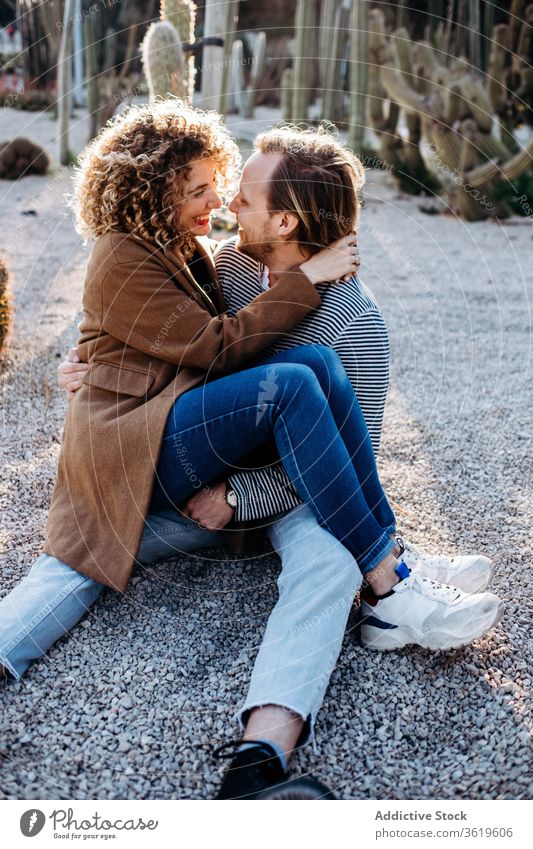 Happy couple hugging in cactus park love happy sunny daytime sit barcelona spain man woman excited relationship embrace cheerful summer together smile rest