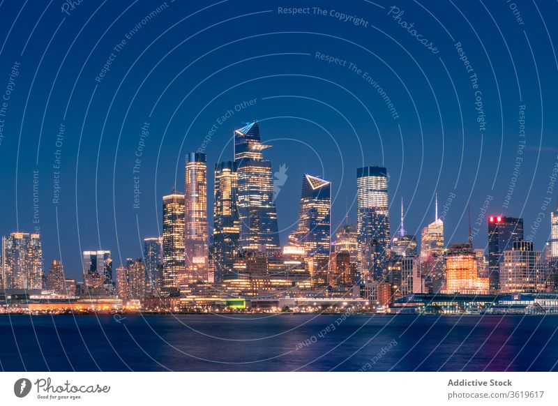 Modern city skyline with illuminated skyscrapers at night cityscape new york embankment coast architecture water building district urban contemporary travel