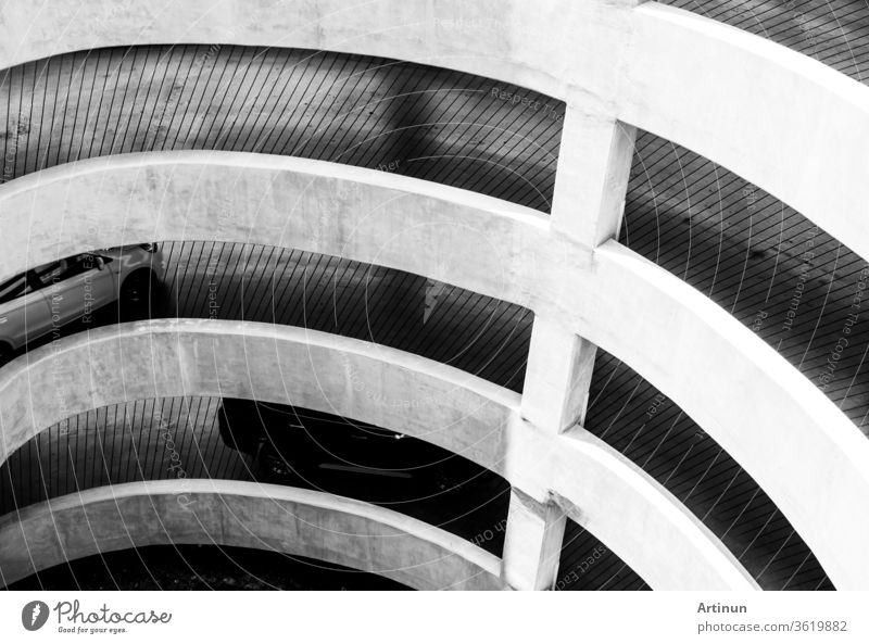 The architecture of the spiral curve and slope way to go to parking lot in the shopping mall. Car driving on concrete road on shopping mall building to car park.