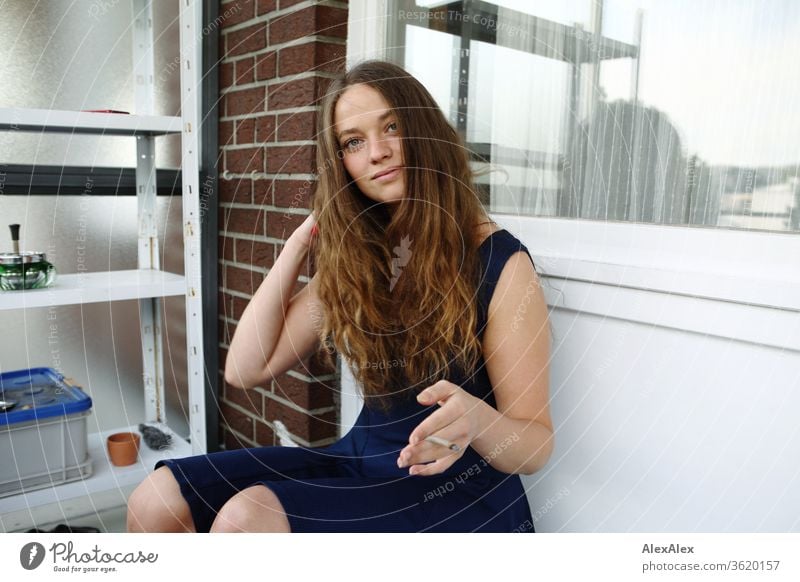 Young woman sitting on her balcony, smiling and smoking a cigarette Woman Youth (Young adults) Feminine already Face 18 - 30 years Human being Colour photo