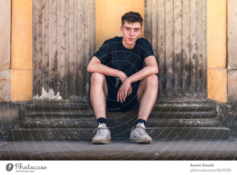 portrait of a young man sitting between two ancient pillars history smile confident outdoor summer grunge old handsome teenager looking boy male beautiful