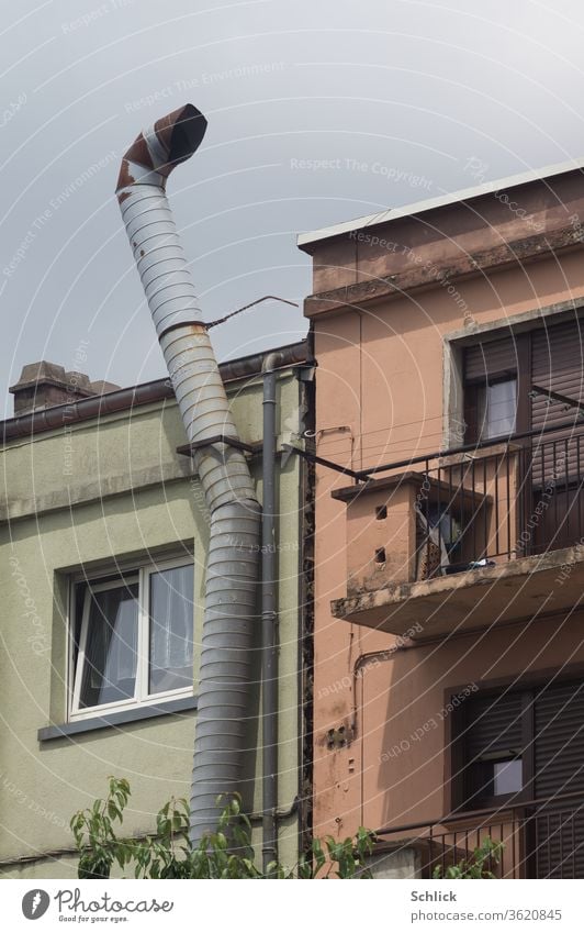 Bent pipe for exhaust air rises into the sky in front of facades in the backyard Outlet air exhaust pipe conduit Backyard Facade broken Bend Old Architecture