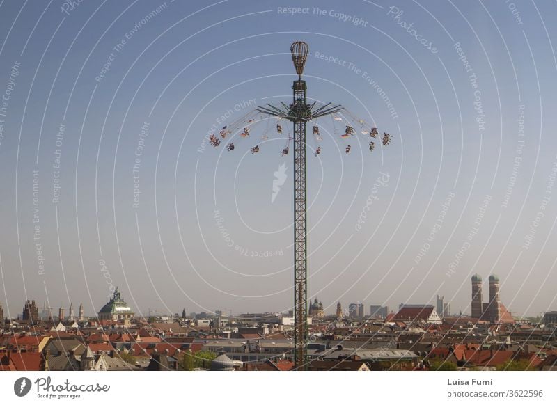 MUNICH, GERMANY -  Panoramic view of Munich and a drop tower, from the spring festival at the Theresienwiese amusement park carousel ride people cityscape