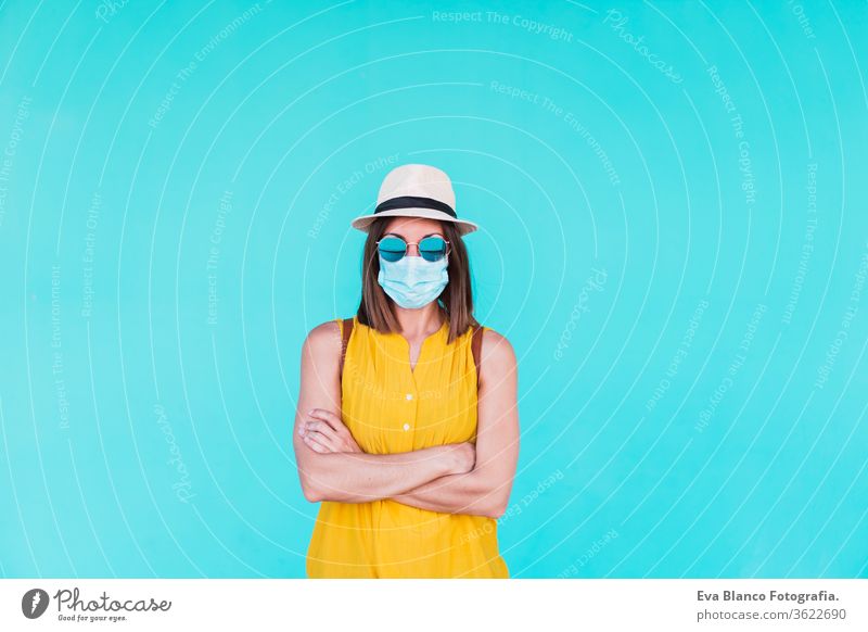 portrait of young woman outdoors over turquoise background wearing protective mask. Summer time and corona virus concept epidemic attitude saying infectious