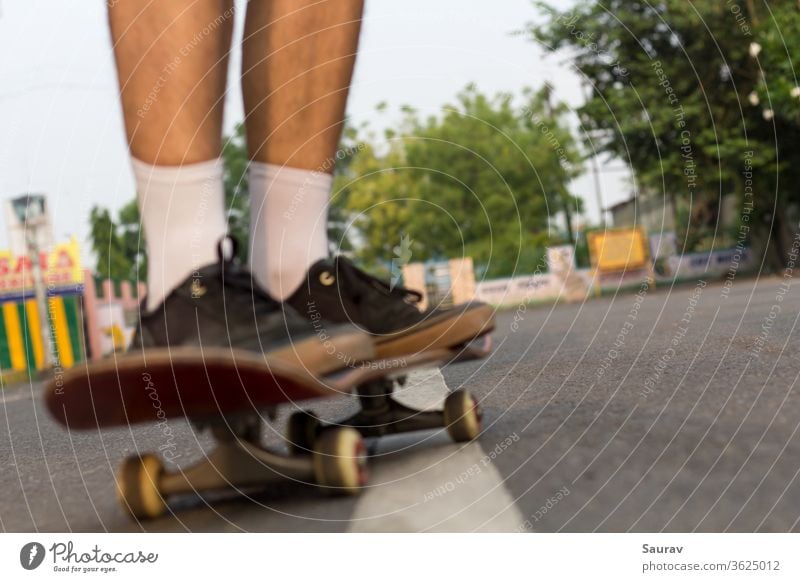 Blurred closeup shot of someone's feet who is cruising on a skateboard on an empty  road. skateboarding recreation lifestyle empty roads summer outdoor lockdown