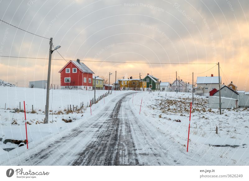 snowy road in Norway on the Lofoten in winter with a lot of snow and ice and cold it is also really icy and frosty on the empty road with the lamppost and the snow markings - is probably also smooth - clouds are also in the sky