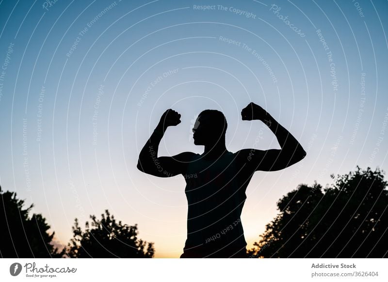 Athletic black man exercising at the park african muscular silhouette fitness strong flexing body muscle biceps arms athlete strength lifestyle chest athletic