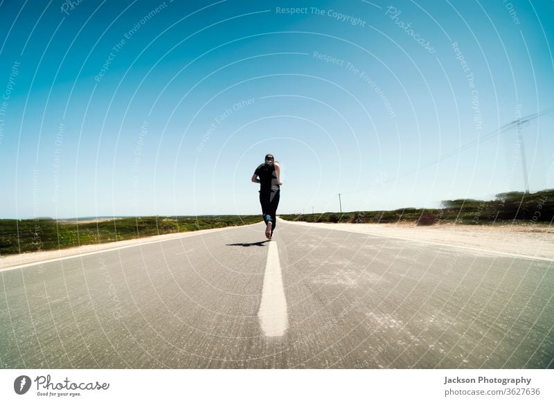 A man running on the middle of empty street runner road copy space asphalt concept line foot bare footed motion blurred away run away portugal