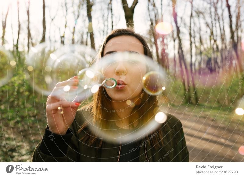 Young woman blowing soap bubbles in the woods. connect networking freedom day natural pretty forest portrait colorful share vision sharing outdoor happy