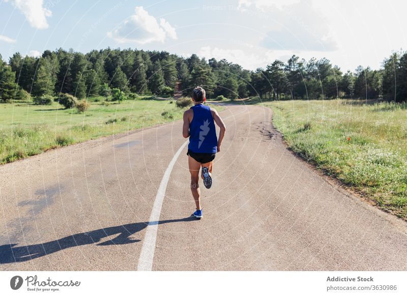 Determined man running on road during workout training fast exercise fitness young sport activity sportswear jog urban healthy body slim strong power