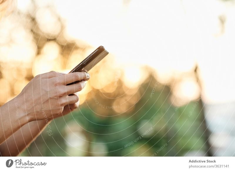 Anonymous woman with smartphone standing in park using enjoy browsing young female trendy lifestyle gadget device chill positive social media smile online