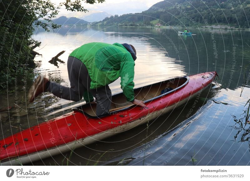 Man jumps into a canoe on a lake Boating trip boat go boating boat tour Boot camp Lakeside Watercraft Rowboat Vacation & Travel Trip Tourism Adventure Freedom