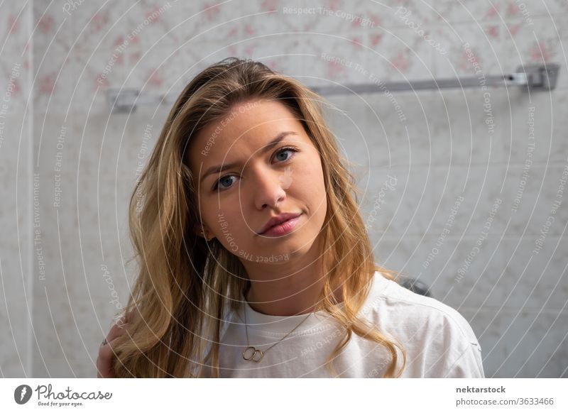 Portrait of Young Blond Woman in Bathroom Looking at Camera woman long hair hairstyle portrait lifestyle looking at camera blond hair young woman one woman only