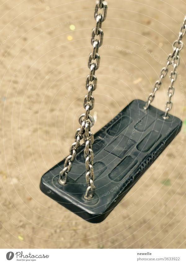 Empty swing on kids playground. vacant chain swing for children in a park on ground background. Close up photo. Corona virus causes empty playgrounds corona