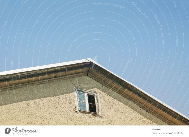 Part of a house gable with a broken, dilapidated, square wooden window in front of a blue sky house gables Window Wall (building) dwell Wooden window Open Glass