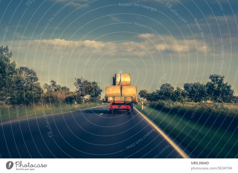 a tractor loaded with hay bales drives on a country road Tractor Hay bale Country road Agriculture Harvest Nature cloudy Summer Colour photo Field fields