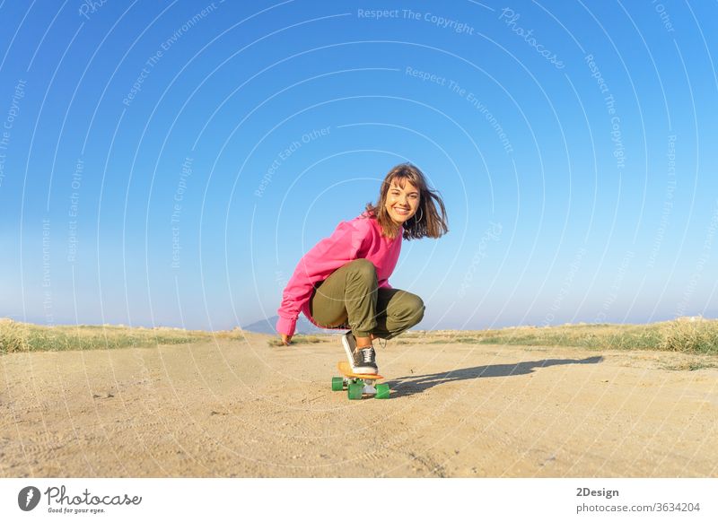 Young woman with pink jersey skateboarding in a footpath urban 1 fun young girl fashion latin hispanic copy space smile 20s speed brunette music cute active