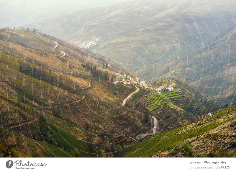 Small illage on the slope of Serra da Estrela mountains, Portugal serra da estrela village portugal field terrace winding rainy road way portuguese panoramic