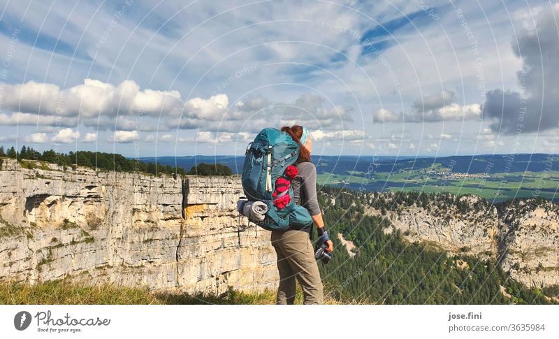 Woman with backpack stands exhausted but proud on the canyon, with her camera ready, she enjoys the view and the sun. Young woman Hiking trekking Rock Nature