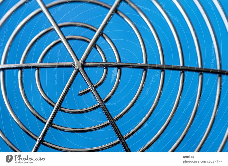 Symmetry / Snail-like windings of a stainless steel skimmer in front of a blue background Slotted spoon Spaetzle lifter Noodle helper High-grade steel Round