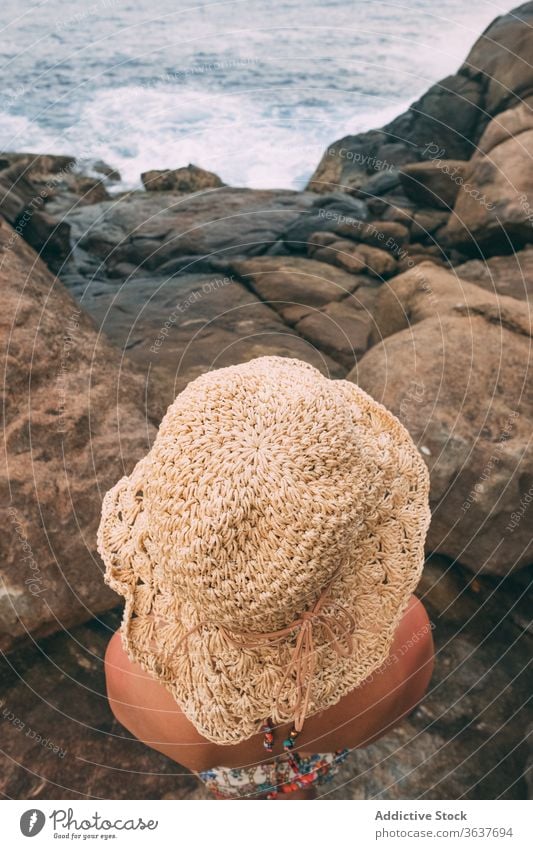 Anonymous traveling woman on rocky seashore holiday summer season admire tourist female stone spectacular seascape vacation nature idyllic tourism coast sit