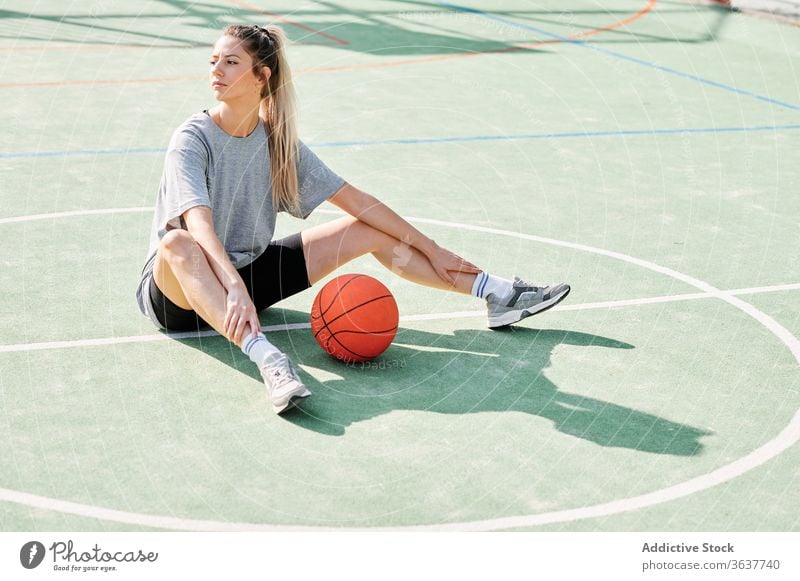 Female basketball player sitting on sports ground woman exercise warm up training prepare court female workout activity game lifestyle wellbeing young power