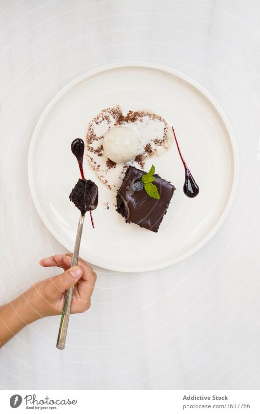 Crop person enjoying chocolate cake with ice cream dessert restaurant pastry delicious sweet ganache confectionery sugar fresh flavor decoration temptation