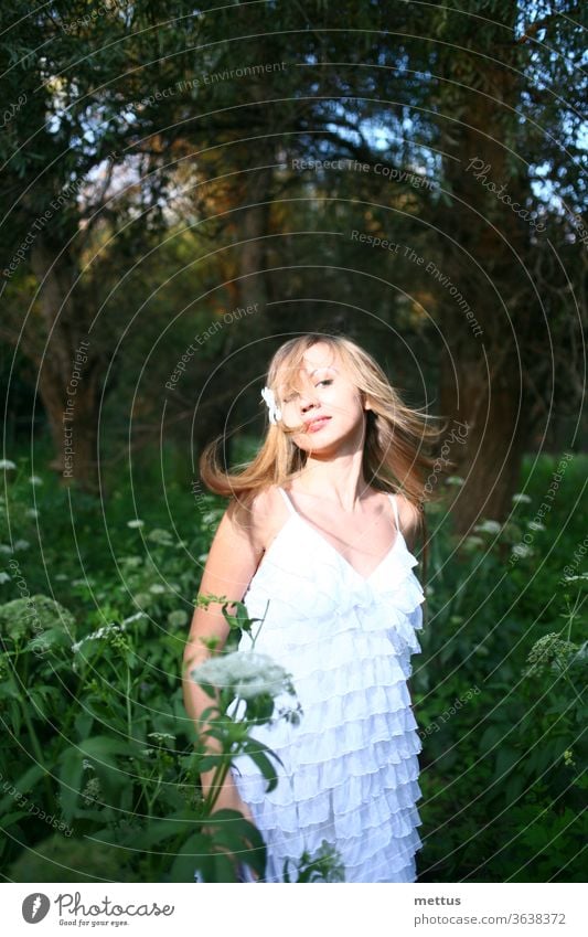 Blond haired lady dancing in the woods in white summer dress with her hair windswept. Emotional and natural image with copyspace. messy hair alone loneliness