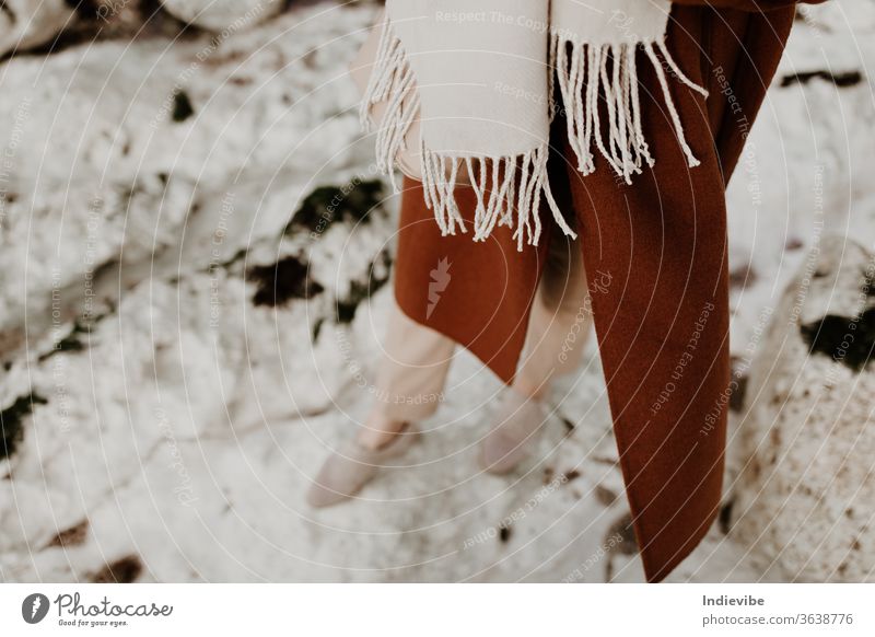 Woman walking outside on white chalk rocks in brown coat and beige scarf woman detail outdoor feet person foot leather shoes natural nature ocean outdoors