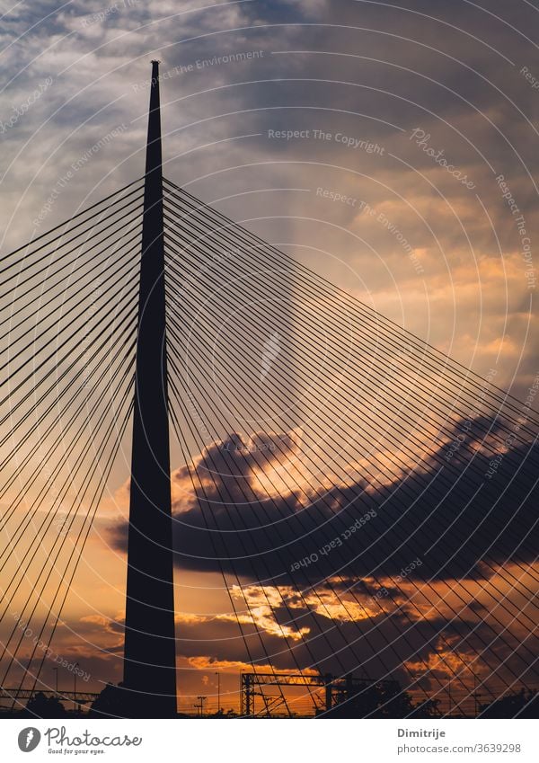 Big suspension bridge tower at sunset - sunrays through the clouds in the background modern architecture sky water steel city blue structure urban building