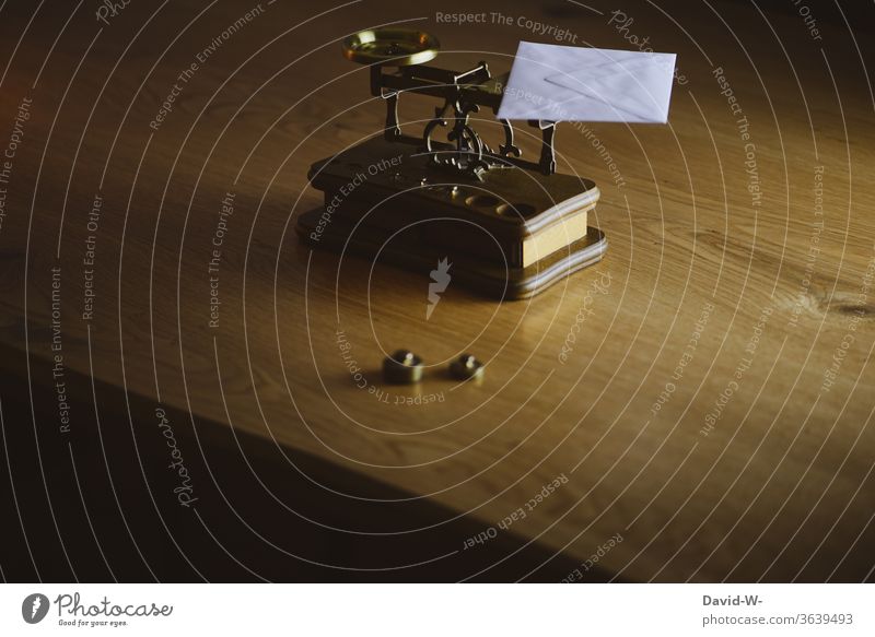 a letter lies on a fine old scale to determine the exact weight Letter (Mail) Scale Weigh Weight Stamp Weights Fine Envelope (Mail) Letter scales