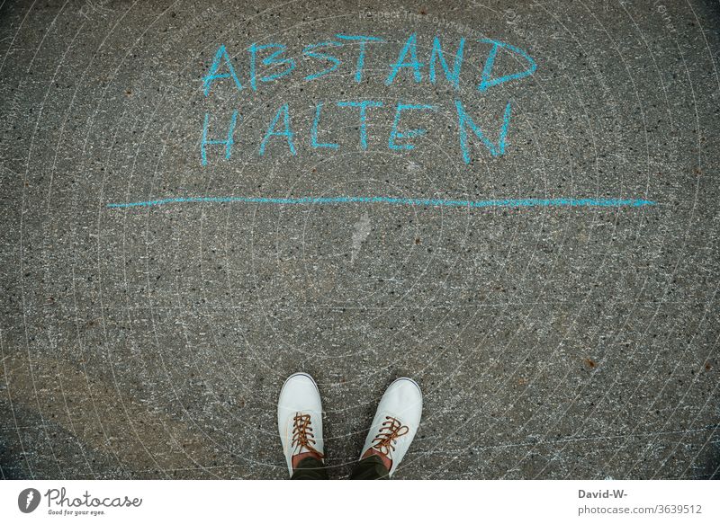 Keep distance - person stands on the street and keeps distance corona Street authored words leap coronavirus Corona virus pandemic Virus Risk of infection