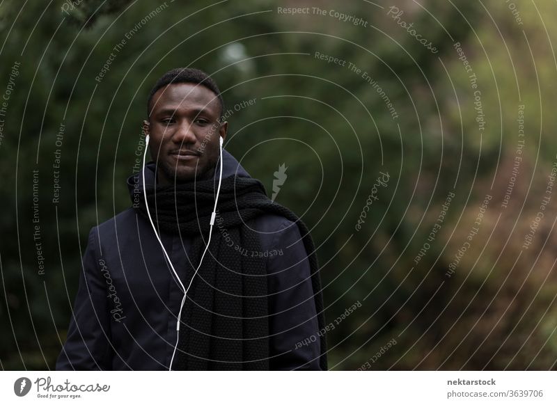 Young Man Listening to Audiobook in Park portrait earphones man African ethnicity black public park listening music audiobook real life model autumn young man