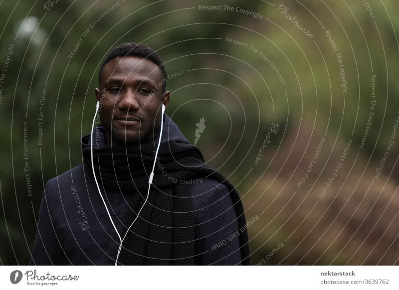 Portrait of Young Black Man Listening to Earphones in Park portrait earphones man African ethnicity black public park listening music audiobook real life model