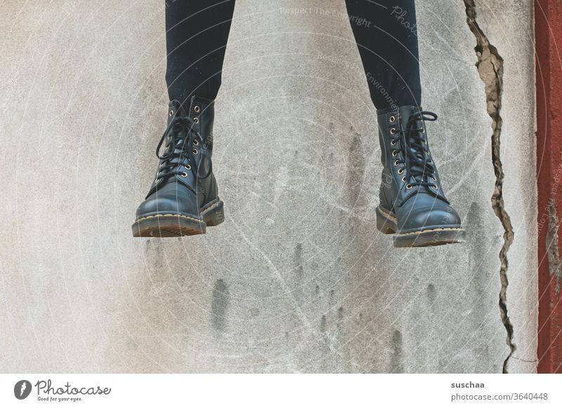 dangling feet of a teenager sitting on a wall | symmetry Legs foot Footwear Boots Cool Sit Youth (Young adults) Wall (barrier) crack in the wall Exterior shot