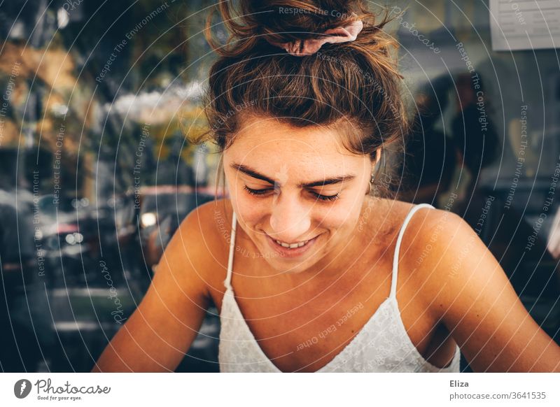 young woman sits outside in summer and looks down Young woman Downward Summer tanned Chignon timid pretty Summery sunshine natural Window pane Pane