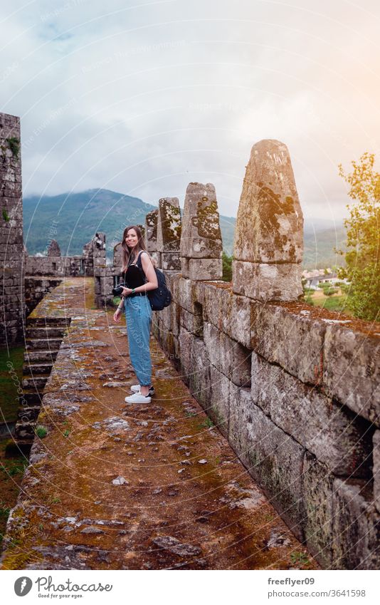 Female tourist with a camera photographer female caucasian blonde ramparts medieval battlements castle tourism travel old abandoned architecture stone galicia