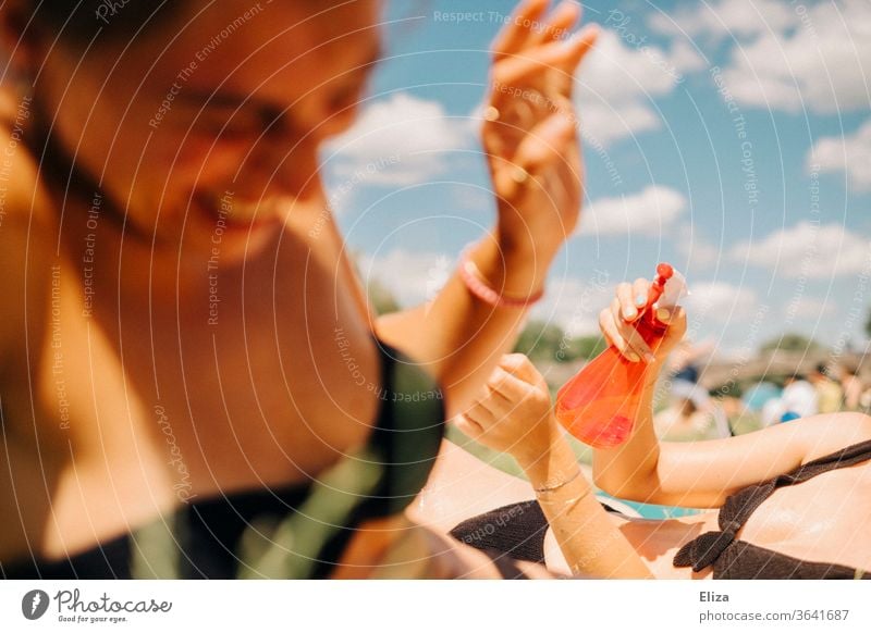 Two young women taking a bath, having fun and splashing each other with water from a spray bottle. Summer and joie de vivre. bathe Spray bottle cooling Water