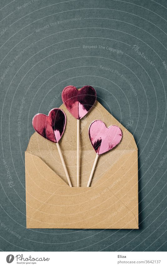 Three pink hearts on a stick peek out of a brown envelope Envelope (Mail) cuddle Best wishes Love Heart Love letter Communicate Copy Space top Letter (Mail)