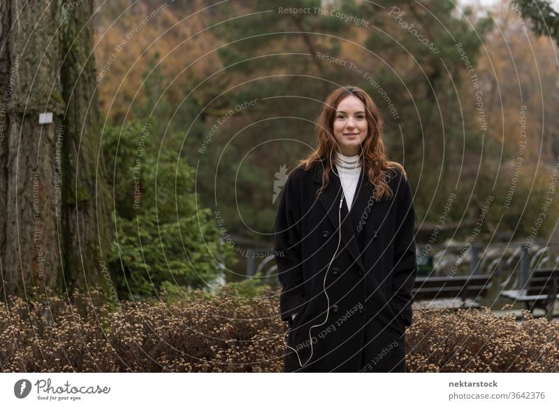 Young Caucasian Woman Posing in Autumnal Park caucasian ethnicity woman female earphones audio music listening brown hair real life model real person urban